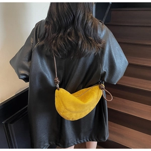 Detail of yellow suede crescent bag featuring a unique brown leather knotted shoulder strap