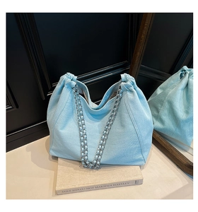 Detail der hellblauen Denim-Tote-Bag mit silberner Kette und Kordelzugverschluss