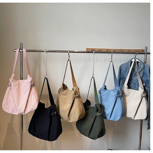 Row of colorful nylon tote bags in pink, black, and blue showing varied color options