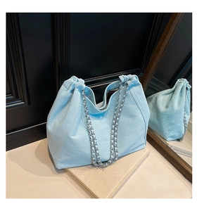 Detailansicht der hellblauen Denim-Tasche mit Kordelzug und silberner Kettenriemen