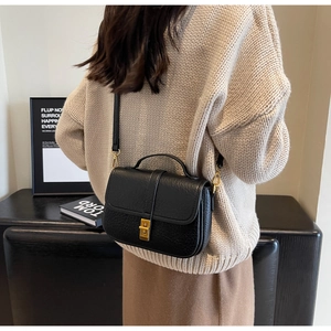 Close-up of black litchi pattern leather small square bag with vintage gold metal buckle