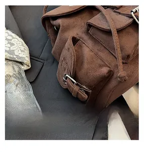 Détail d'un sac à dos en daim marron avec cordon de serrage et boucle en métal robuste