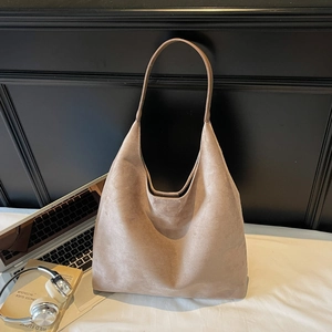 Close-up of a large khaki suede tote bag styled with a laptop and headphones for work