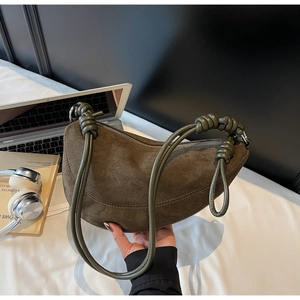 Detail of suede crescent bag showing knotted leather strap and smooth texture