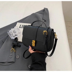Detail of black vintage saddle bag with fine texture and golden metal twist-lock