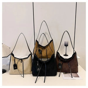 Detail view of suede tote bags in four colors with slender leather straps and bow ties