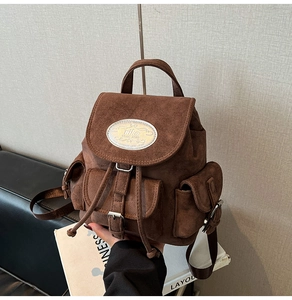 Vue détaillée d'un sac à dos en daim marron montrant le logo nika et la poche avant