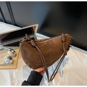 Detail of brown suede crescent bag featuring unique rope knots and silver metal zipper