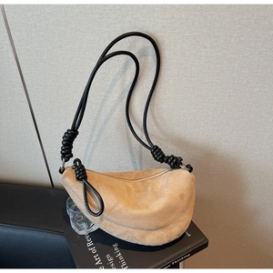 Detail of light brown suede croissant bag with black decorative knotted rope shoulder strap