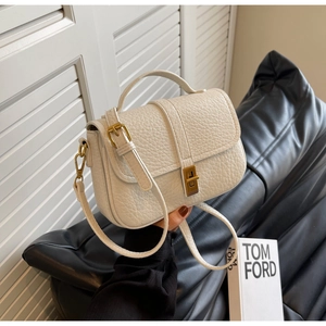 Detail of cream white leather bag with vintage gold lock and adjustable strap