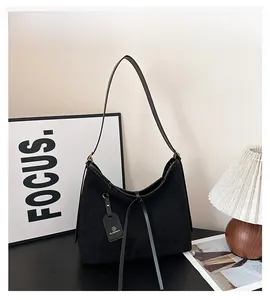 Detail view of black suede crescent bag with fringe tassels and sleek leather strap