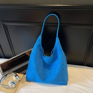 Detail of royal blue suede tote bag with matte texture next to laptop and headphones