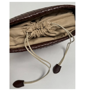 Detail der dunkelbraunen geflochtenen Leder-Beuteltasche mit beigem Canvas-Innenfutter