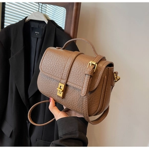 Detail of vintage brown lychee grain handbag with gold twist lock and top handle