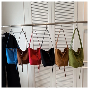 Detail view of suede drawstring bucket bags in multiple colors with slim shoulder straps