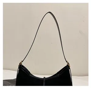 Detail of the black suede crescent tote bag showing the leather strap and gold metal buckle