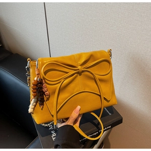 Detail of yellow bow shoulder bag with colorful wooden beads and silver chain strap