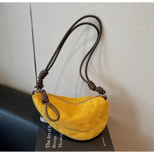 Detailed macro of a yellow suede crescent bag with dark brown braided rope handle