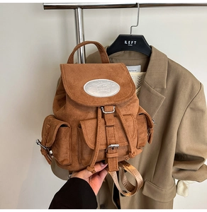 Détail d'un sac à dos marron en similicuir avec plusieurs poches et boucles argentées