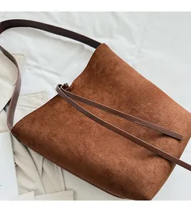 Détail d'un sac seau en cuir brossé marron avec texture souple et bandoulière réglable