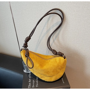 Detailed macro view of yellow suede texture and brown twisted leather strap on handbag