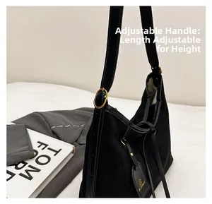 Detail of black suede tote bag with adjustable strap and metallic oval buckle