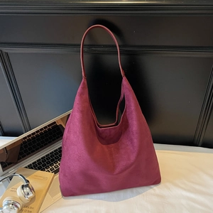 Detail of burgundy faux suede hobo bag with smooth leather strap in lifestyle setting