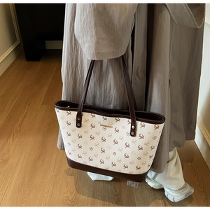 Detail der großen Shopper-Tasche mit Elchmuster, cremefarbenem Korpus und braunen Griffen
