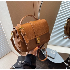 Close-up of brown litchi grain leather texture and vintage gold metal lock on handbag