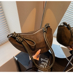 Close-up of brown suede hobo bag with unique knotted strap and metal zipper detail
