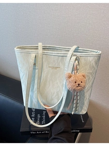 Mint green crinkled leather tote bag with a plush bear charm and gold lettering