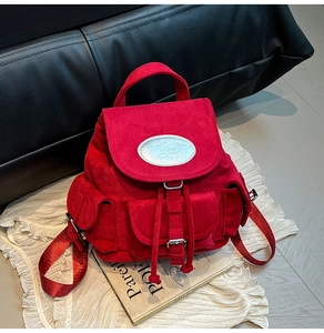 Détail d'un sac à dos rouge mat en daim avec logo métallique et fermeture à cordon