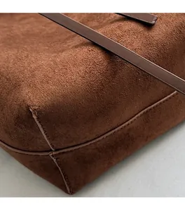 Macro shot of dark brown suede bucket bag showing precise stitching and corner texture