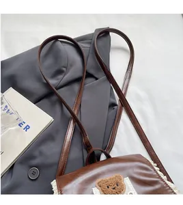 Close-up of adjustable leather shoulder strap on brown lace bear backpack detail