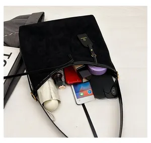 Top view of large black suede tote bag showing tablet, wallet, and daily essentials inside
