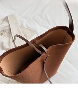 Detail view of brown suede bucket bag featuring functional drawstring tie closure design
