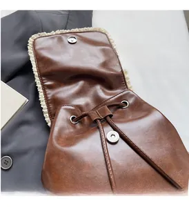 Detail of vintage brown leather backpack with lace trim and silver magnetic buckle closure