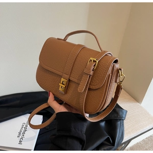 Detail of vintage brown textured leather handbag with gold metal clasp and top handle