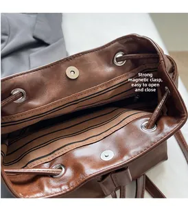 Detail of brown faux leather backpack featuring magnetic snap closure and striped lining