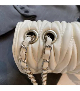 Makro-Detail der weißen Steppledertasche mit silbernen Ösen und Kettenriemen