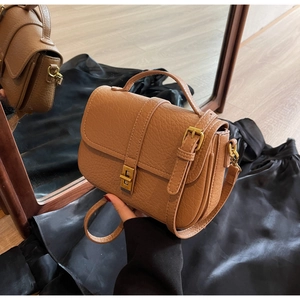 Close-up of brown textured leather bag with vintage gold metal twist lock and handle