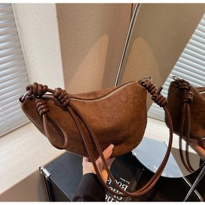 Detail of dark brown suede crescent bag with knot shoulder strap and silver zipper