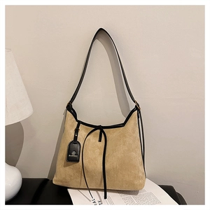 Detail of camel suede tote bag showing black leather piping and decorative bow tie