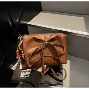 Brown pleated leather shoulder bag with a bow knot and beaded tassel charm detail