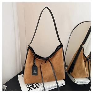 Close-up of vintage brown suede tote bag with black leather trim and decorative tag