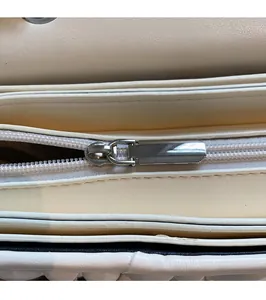 Detailansicht des silbernen Metallreißverschlusses und Innenfutters der cremefarbenen Tasche