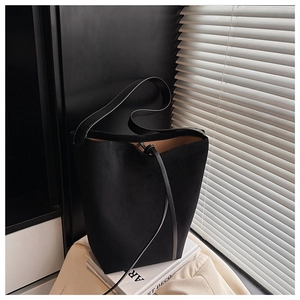 Close-up of black suede bucket bag with drawstring and warm yellow leather lining