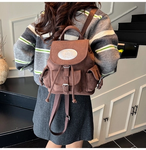 Détail du sac à dos en daim marron montrant la texture mate et les poches extérieures