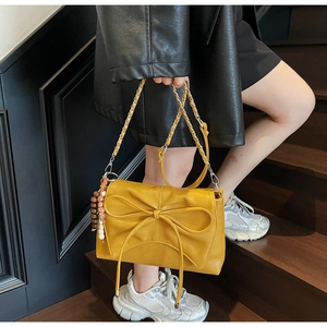 Detail of ginger yellow crossbody bag with bow, ethnic beads and silver chain strap