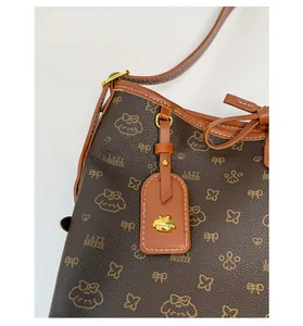 Detailansicht der braunen Monogramm-Tasche mit Lederpaspeln und goldenen Metallbeschlägen